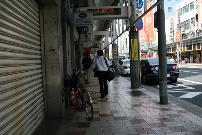 several people walking on the sidewalk next to a store