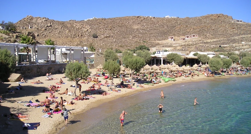 a bunch of people on the sand near some water