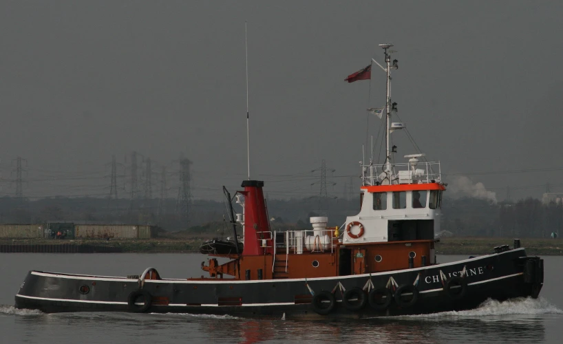 a tugboat traveling in the water with two flags on it's mast
