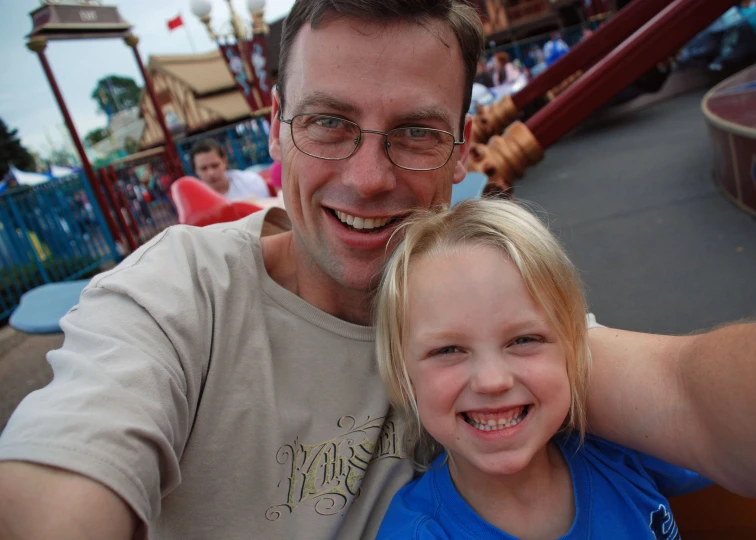 a man with glasses smiles while taking a selfie with a girl