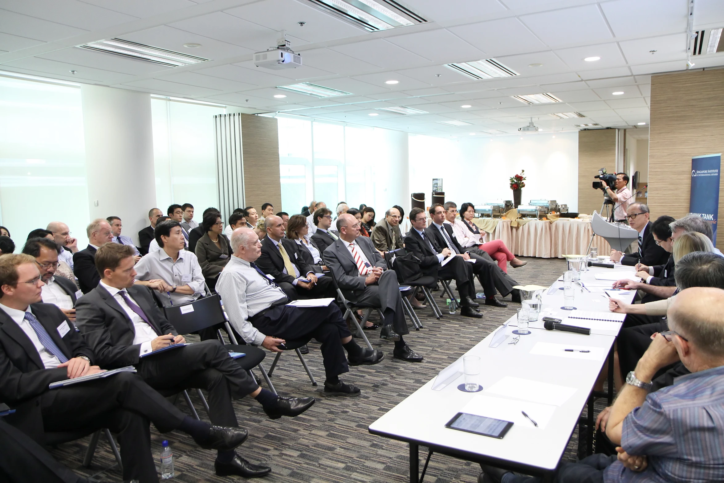 a room full of business people are listening to a man speaking at a podium