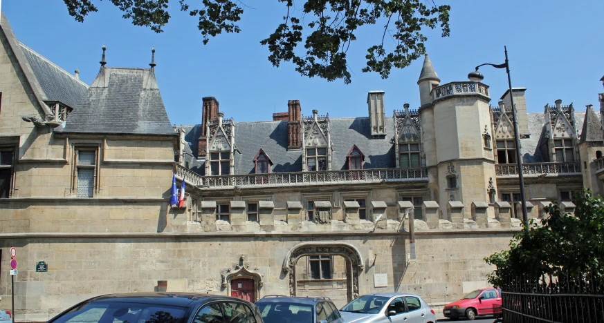 several cars are parked near a castle with a clock on the front