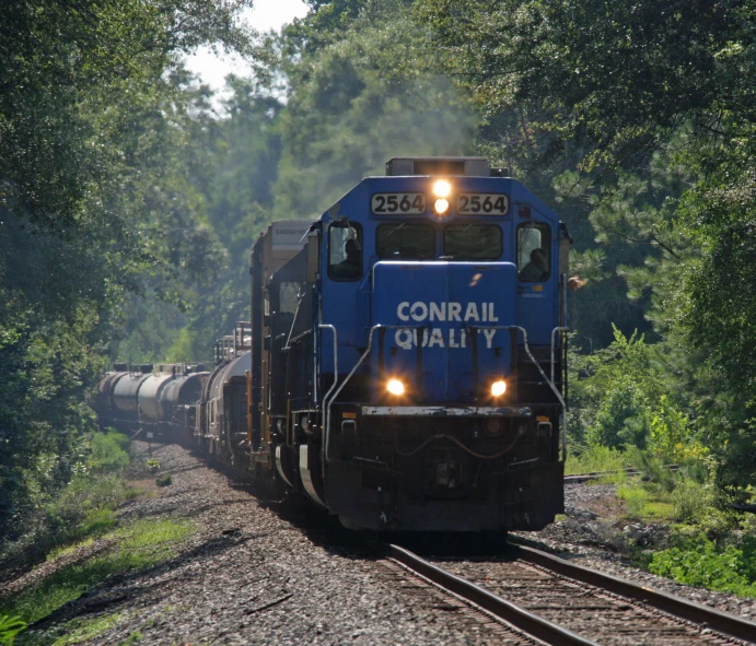 the front of a train with lights on driving down the tracks