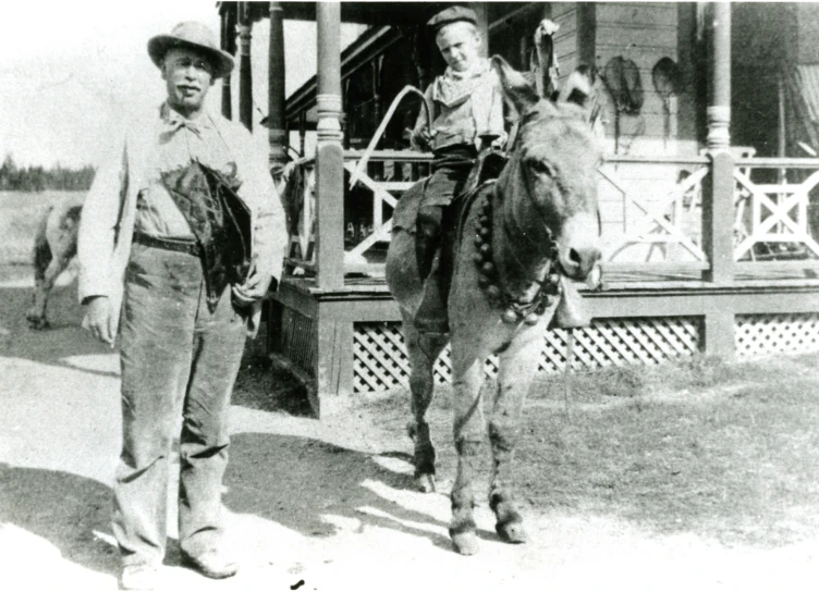 a man standing next to a donkey on top of a field