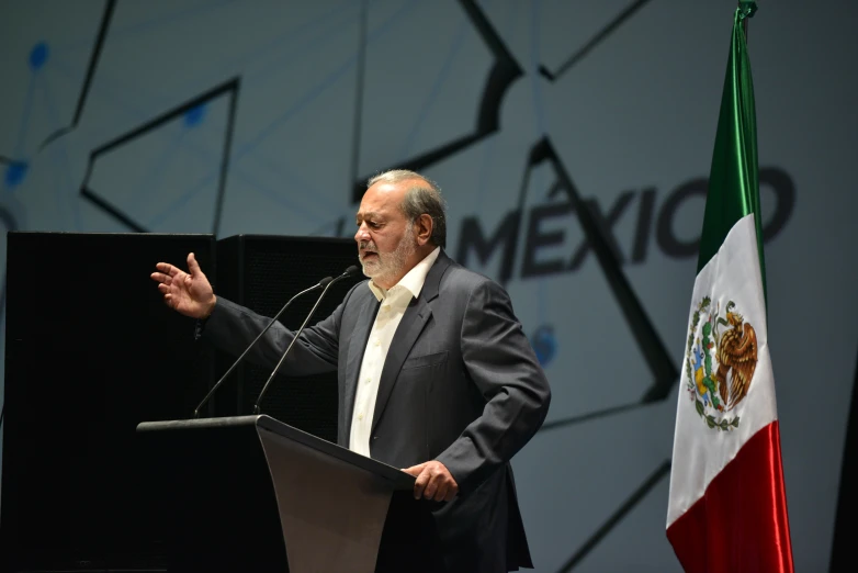 the man is speaking at an event while holding his hands out