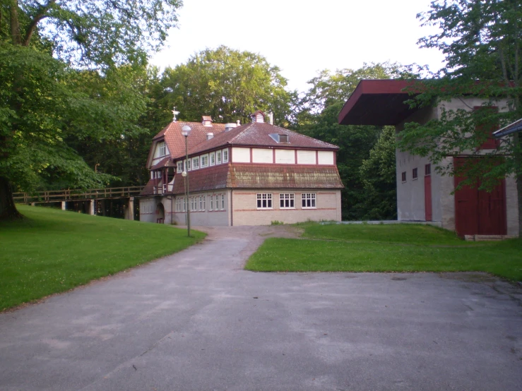 a large driveway with a lot of grass and house in the background