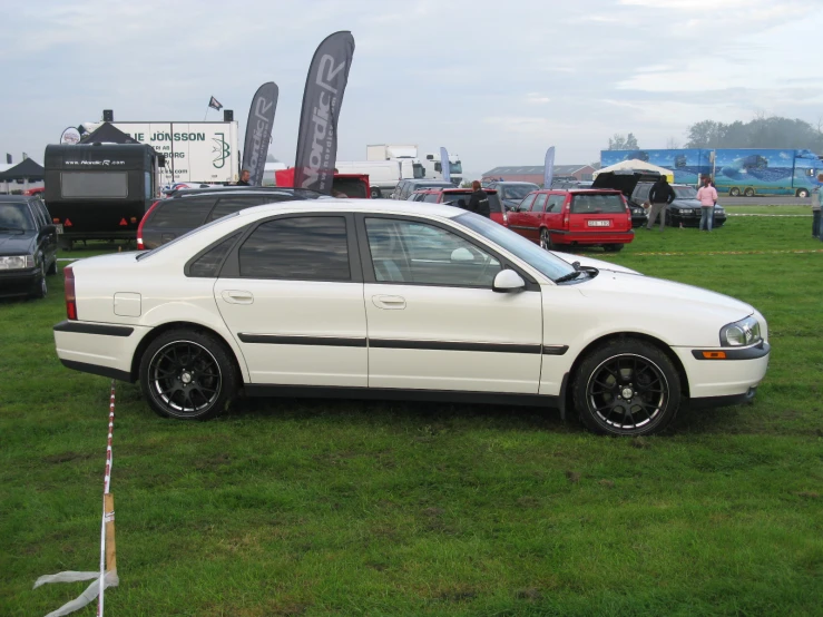a white car is parked on the grass at an auto show