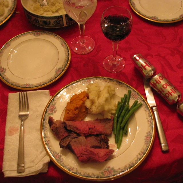 dinner setting including food with wine glasses, silverware and a bottle