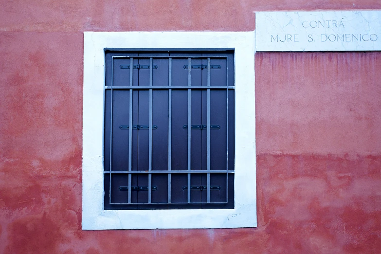 a red building with a metal window and a white wall