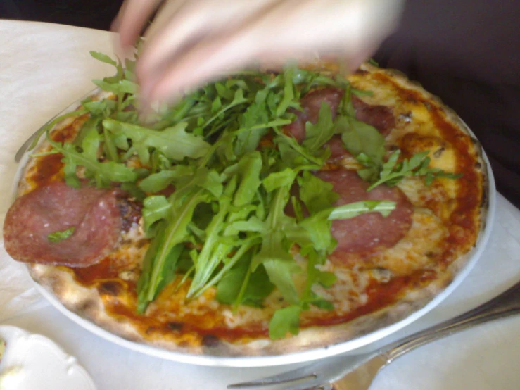 person grabbing food from a dish with spinach