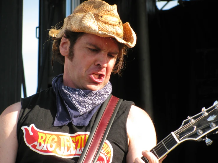 a man with a hat and guitar on stage