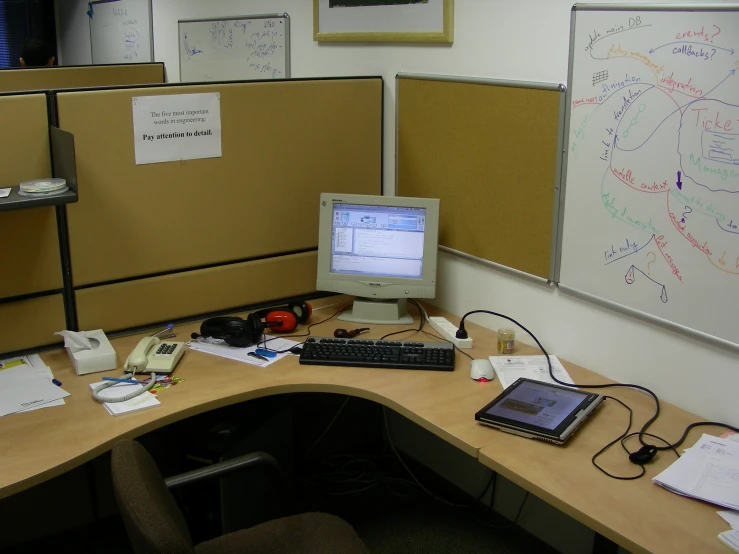 an office cubicle with computer, phone and many notes on it