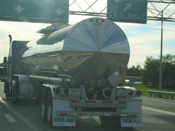 a tanker truck traveling down the highway with an exit only sign