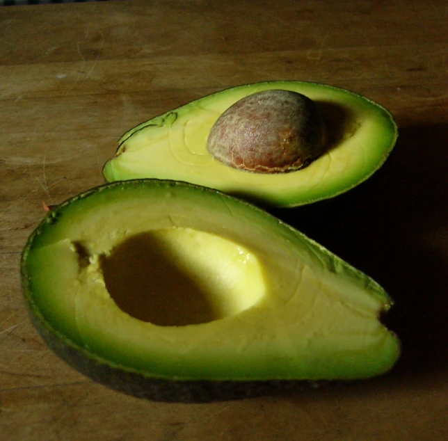 an avocado cut in half on a  board