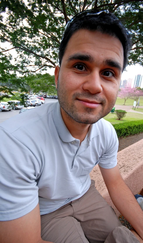 a man poses in front of a park with trees