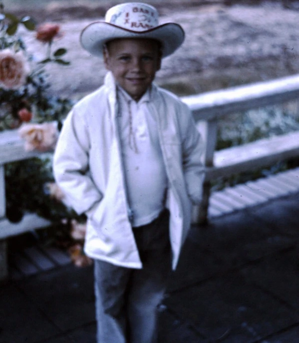 an older man wearing a hat standing on the sidewalk