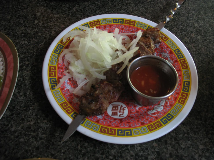 a plate topped with meat and vegetables sitting next to dipping sauce