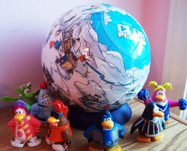 a very small group of small plastic toys sitting around a big ball