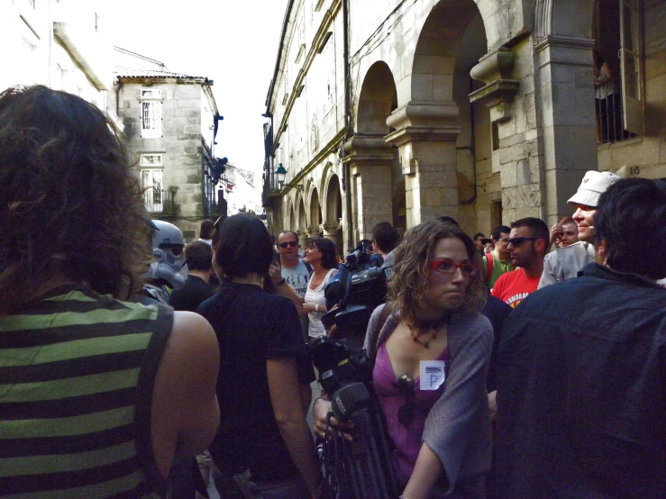 a crowd of people walk in a narrow urban street