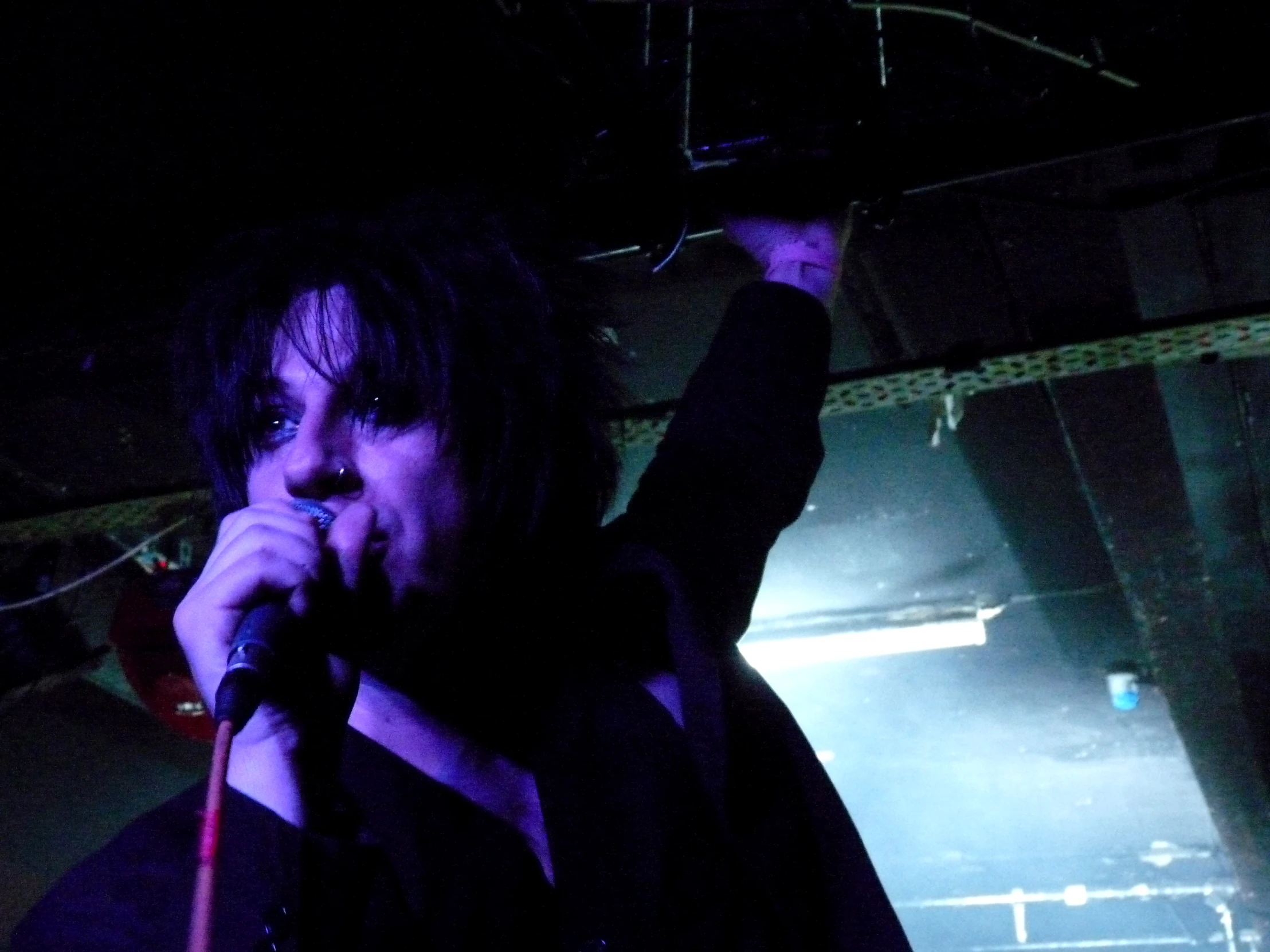 the man with microphone is singing in front of a dark background