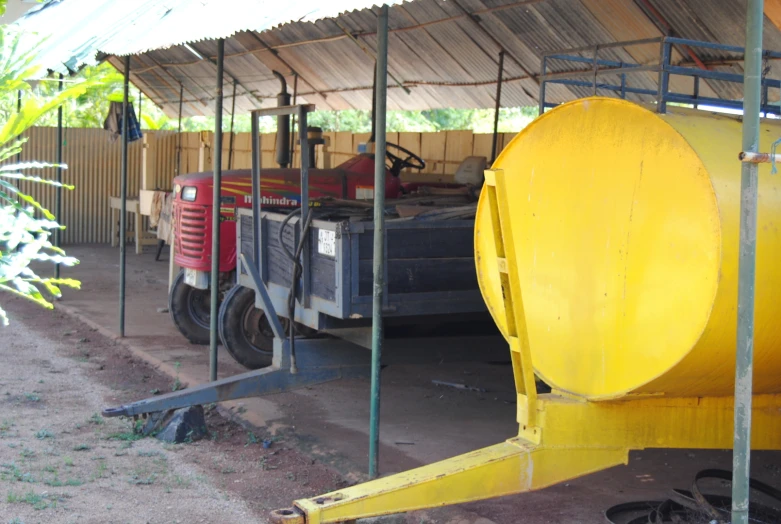 two yellow trucks are under the roof and some poles