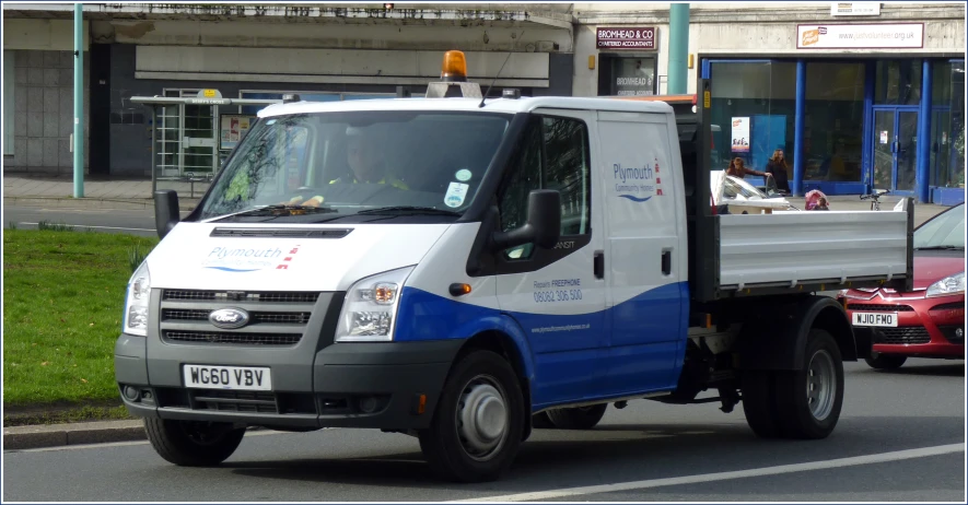 the white and blue utility truck is driving down the street