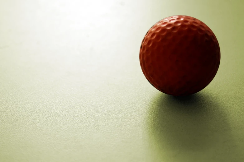 a red ball sitting on top of a green table