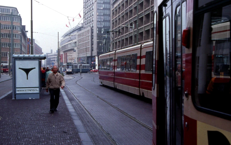 an elderly man walking down the sidewalk near an electric trolley