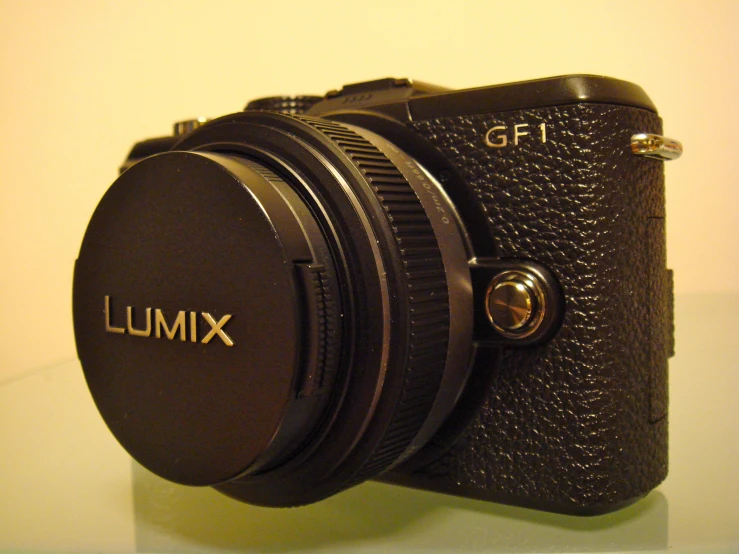 a black camera with the lens up is sitting on a glass table