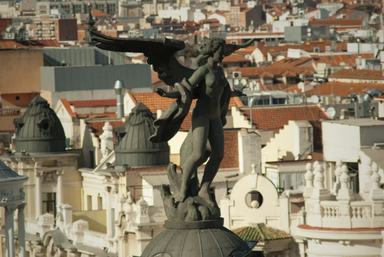 an old - fashioned statue stands in front of the city's rooftops