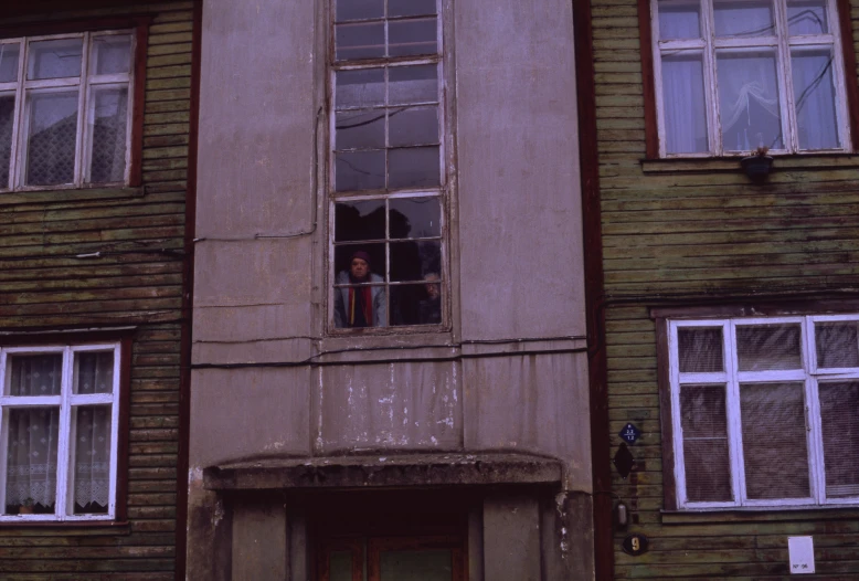 two people look out the window of a brown building