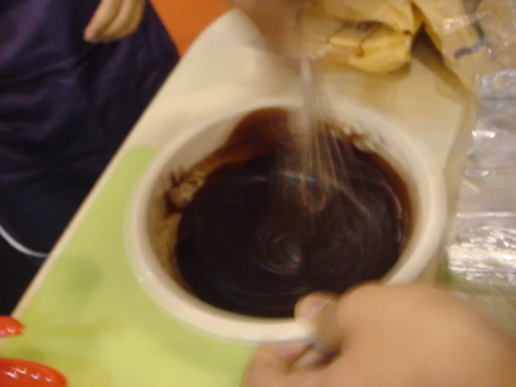 a person sprinkling chocolate into a bowl