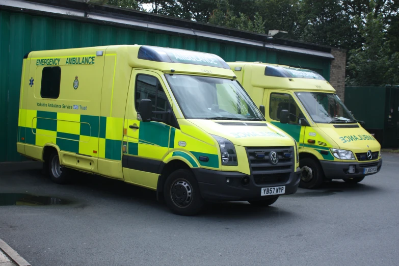 a pair of ambulances sitting in front of a green building
