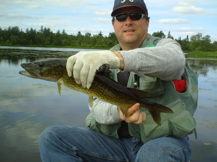 a man holding onto a large fish while sitting on the ground