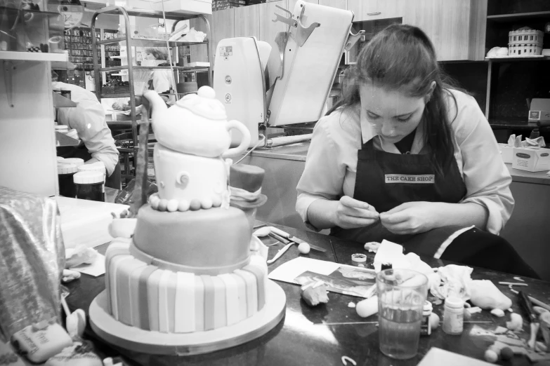 there is a woman in the kitchen decorating a cake