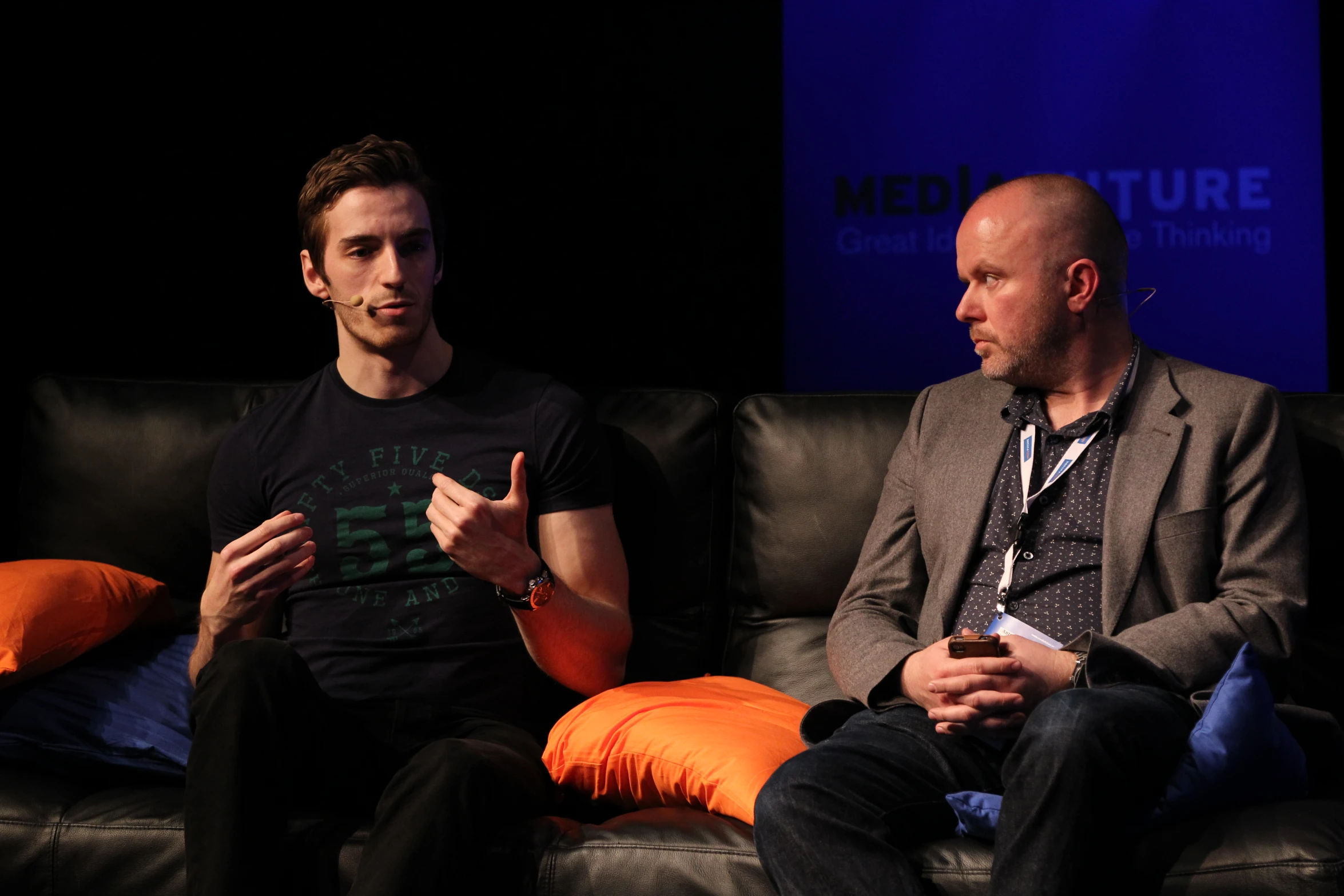 two men sitting on top of a couch talking