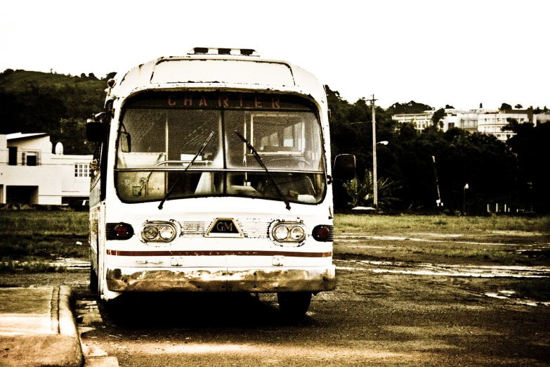 old bus with broken windshield parked on a road
