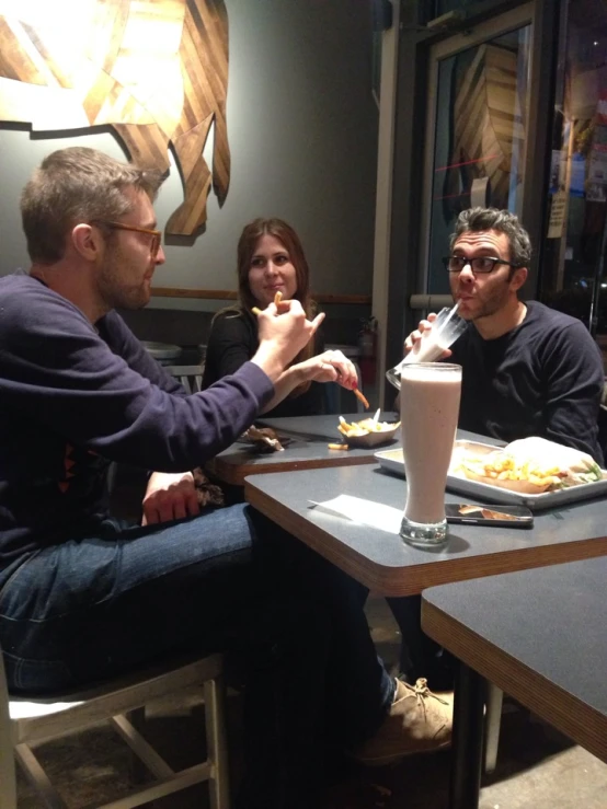 several people sitting at a table and eating and drinking