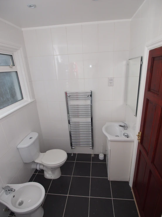 an empty white bathroom with toilet, bidet and sink