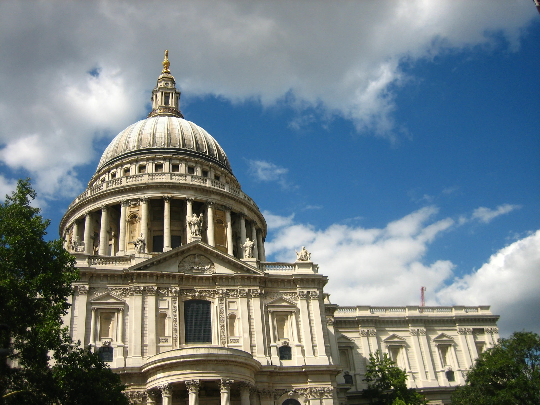 a dome sitting in the middle of a building under a blue cloudy sky