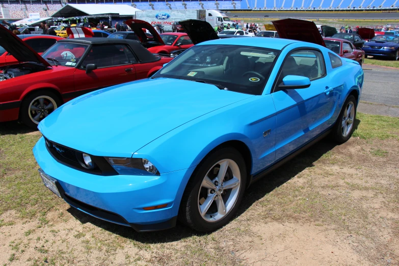 a bright blue mustang sits among other cars in a parking lot