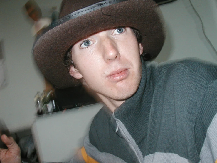 young man wearing hat looking over shoulder to the camera