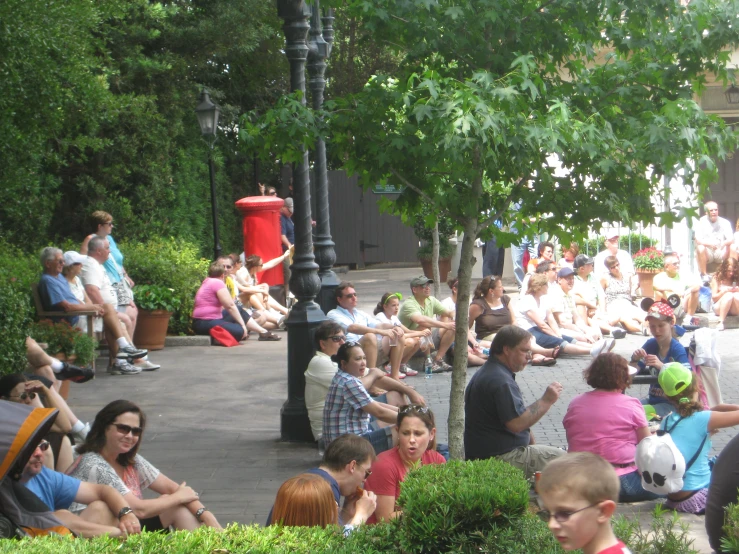 a crowd of people sitting on benches near trees