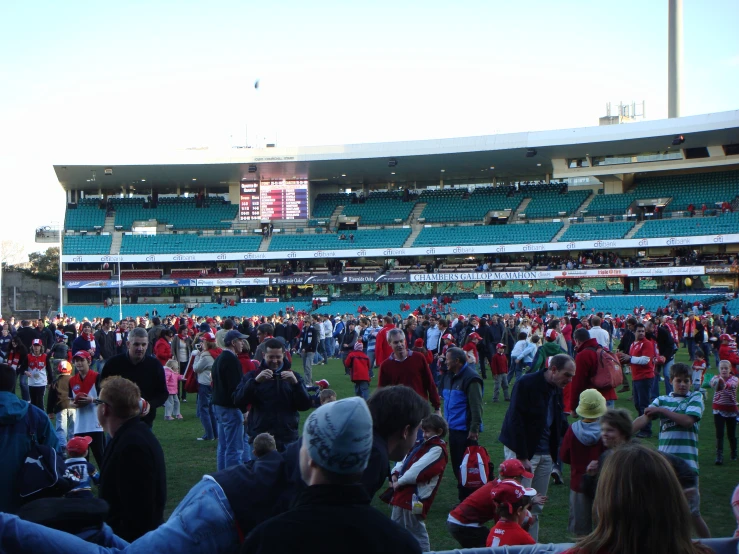 a large crowd stands in a sports stadium as their names are listed on the scoreboard