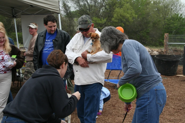 a group of people standing around each other while holding dogs