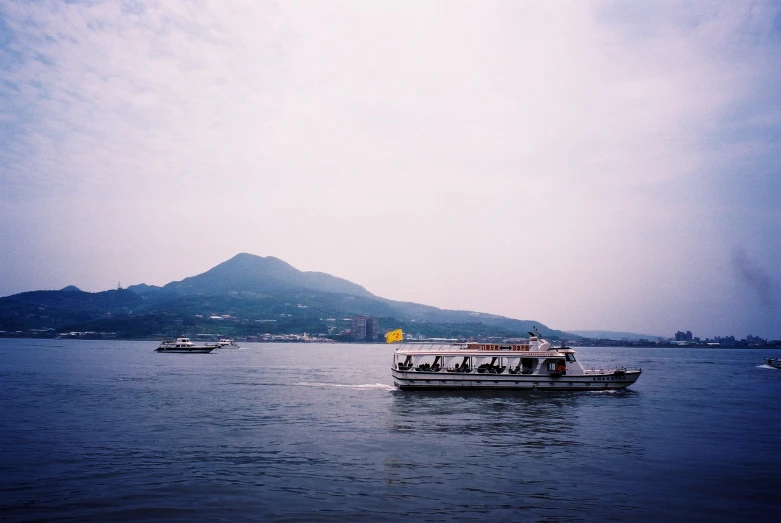 a boat floating on the water with mountains in the background