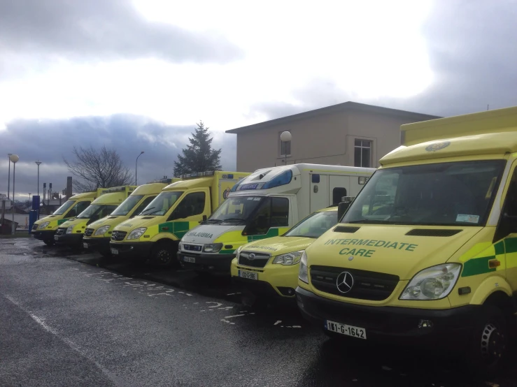 a row of yellow and black ambulances parked in a parking lot