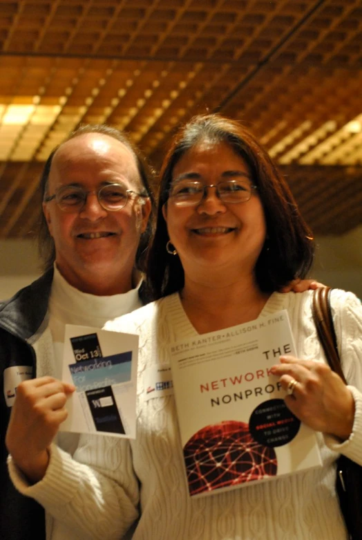 two people that are standing together with book