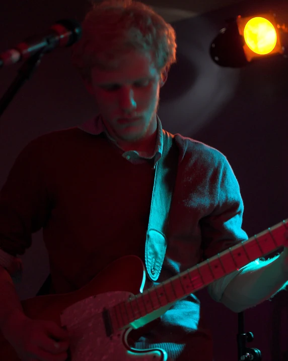 a man playing a guitar while standing under a spotlight