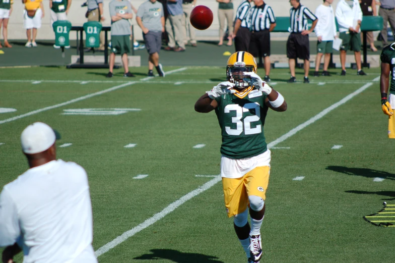 a player wearing green jersey holding a football in both hands